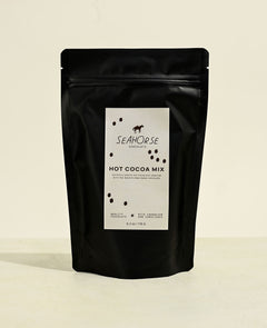 Black packaging of Seahorse Hot Cocoa Mix on a beige background